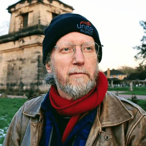 A photo of John Cunnison, looking good. John is accessorising with a "Unite" beanie, and a red scarf.